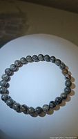 Top view of natural yooperlite gemstone bead stretchy bracelet showing grey, black and white speckled round beads approximately 6mm diameter