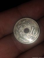 Obverse side of coin showing denomination "10 CEs" and leaf decoration around central hole.