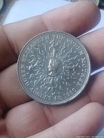 Photo of coin's reverse side showing Queen Elizabeth The Queen Mother profile with radiating rays and inscription around the edge.