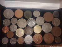 Top-down view of mixed coin collection in a case, showing various sizes and metals including silver and copper colored coins