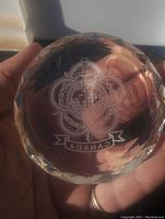 Top view of the crystal paperweight showing the detailed engraved emblem including globe, sword, plane, and the word 'CANADA'.