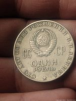 Reverse side of USSR one ruble coin with state emblem and inscription about Lenin's birth centennial.
