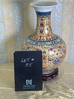 Front and side views of the globular Asian gold vase with floral and symbolic patterns on wooden stand.