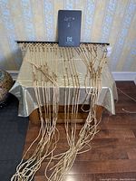 Front view of the light-colored, knotted string beaded curtain arranged on a table with black hanging rod visible