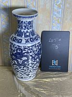 Front view of the blue and white porcelain vase with detailed dragon and floral patterns, showing a flared rim and geometric bands near the neck.