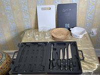 Full view of collection showing glass tumblers, plates, cutlery set in case, and CorningWare baking dish on tabletop