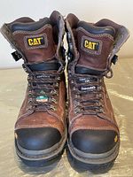 Front view of brown CAT work boots with composite toes and laces, size 7.