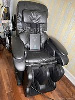 Front view of black leather Panasonic massage chair showing seat, backrest, armrests and foot massager.