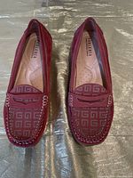 Top-down view of pink penny loafers showing patterned vamp, stitching, and branding on insole.