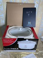 Slow cooker in open box with lid resting inside, showing interior ceramic pot and partial product package details.