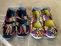Two pairs of colorful woven Snuggies slip-on shoes placed side by side showing the top and front view of each pair.