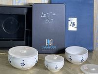 Photo showing the three ceramic storage bowls with lids arranged outside their open original blue packaging box. Each bowl has a white base with blue floral/berry pattern.