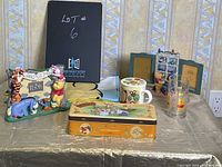 Full view of the collection on green table, showing cookie tin, ceramic cup, glass, photo frames, figurine, and flag.