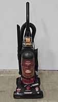 Front view of the Bissell PowerForce Turbo upright vacuum showing the dust container and attached hose.