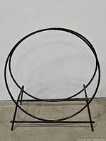 Front view of black steel circular log rack showing its round frame and curved support bars.