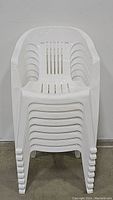 Stacked view of 8 white plastic outdoor chairs showing front profile and stacked structure.