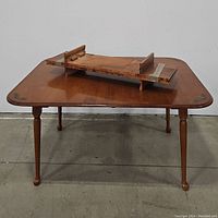 Front view of the retro wooden dining table showing four legs and painted accents on corners.