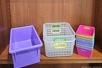 Photo showing all items together: large purple container, two translucent mesh baskets, and stack of multi-colored small containers.