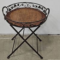Side table showing full structure, metal top with scrollwork and woven insert.