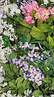 Close-up showing white, pink, and purple artificial wisteria flowers with green leaves in a tub