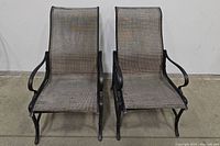 Two woven metal patio chairs side by side showing full front view including frame and mesh seating.