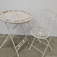 Wrought iron bistro table and chair set, showing full side angle with matching design and color.