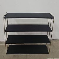 Front view of black metal 4-tier shelf showing overall structure and spacing of shelves