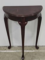 Front-facing view showing the half moon shape, dark wood finish, and claw foot design of the legs.