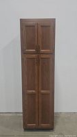Front view of the tall wooden kitchen cabinet with four doors closed.