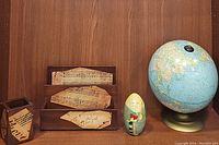 Desk items including small globe, wood mail organizer, pencil holder and vintage nesting egg all arranged on shelf