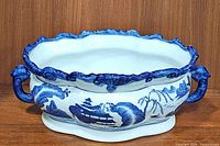 Full view of the large porcelain oval planter showing blue and white traditional scenic design and handles on each side.