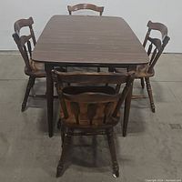 Front view showing rectangular dining table with 4 spindle back chairs around it, dark wood finish with some wear visible