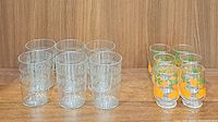 Full view of all 12 glasses, 6 etched clear glasses on left, 6 orange and leaves design glasses on right, arranged in two rows