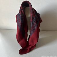 Red silk scarf draped on mannequin showing overall color and pattern scheme.