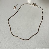 Photo showing the 10K gold chain bracelet alongside one stud earring with a small clear stone.