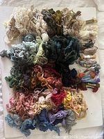 Collection of approximately 170 assorted wool tapestry yarn skeins in various colors, tied and some in packaging.