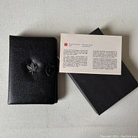 Black leather case embossed with a silver maple leaf, Royal Canadian Mint informational card, and black outer box.