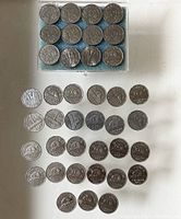 Canadian nickel coins, some stored in a box and some loose, arranged on a white surface. Coins vary in date from 1922 to 1936 in box, later dates loose.