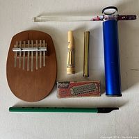 Full lot of musical instruments and toys including kalimba, flute, harmonica, and kaleidoscopes on white surface.