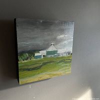 Front angled view of original oil painting on board showing the farmland scene with green barn and silo under cloudy sky.