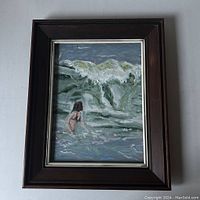 Full view of the framed oil painting showing the ocean wave with swimmer and dark wood frame with silver inner edge