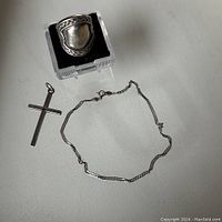 Full lot showing ring on display stand, cross pendant, and ankle bracelet laid out on white background.