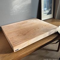 Cutting board displayed on table showing side thickness and natural oak wood grain.
