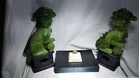 Ring displayed between two green jade foo dog statues