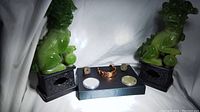 Photo showing all items in the lot on a black base with two green jade-style Foo Dog statues for display.