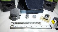 Photo showing two skull rings, cuff bracelet with magnetic ends on a display, Cuban link bracelet, and stainless steel money clip with Hematite cabochon placed with ruler for size reference.