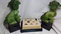 Photo showing 8 rings on a cream jewelry display stand placed between two green Foo Dog statues. Shows overall presentation and number of rings.