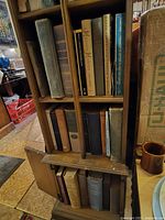 Books arranged on wooden shelves, various titles visible including larger volumes and some with dust jackets.
