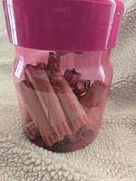 Pink translucent coin counter bank filled with rolled pennies inside, showing the volume of rolls in the container.