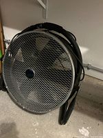 Large industrial floor fan showing metal frame and large blades enclosed in grille